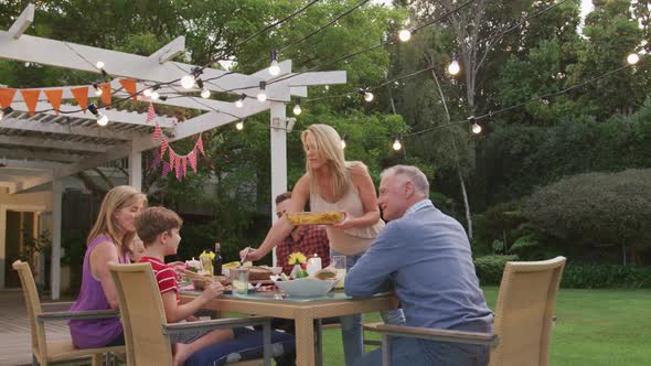 Three generation family enjoying lunch outdoors alt