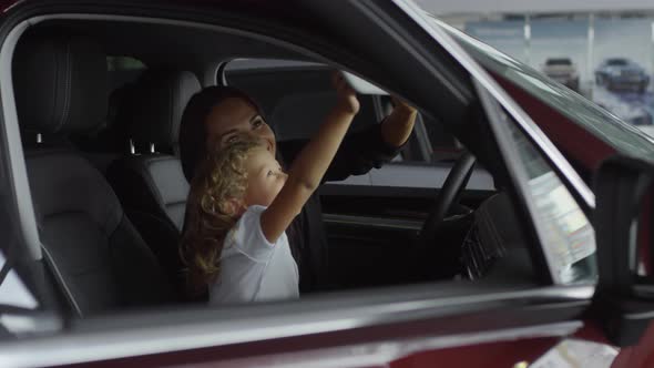 Happy Mother and Daughter Discussing Interior of Car in Auto Showroom alt