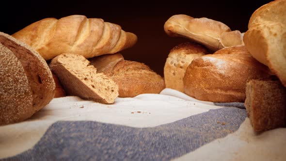 Assortment of Fresh Bread on Tablecloth Zoom in Video alt