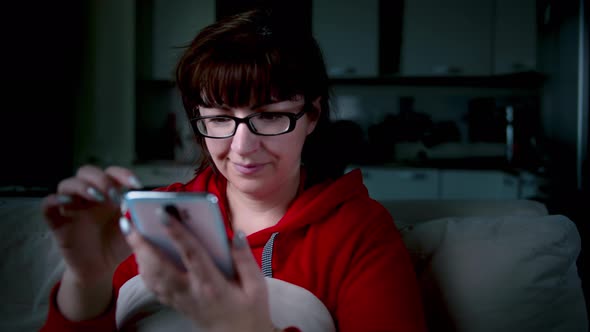 Woman with Glasses at Home Uses Phone Chat with Friends Read Some Information in the Evening