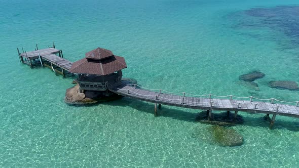 Aerial of gazebo on a dock out in the ocean on the rocks. alt