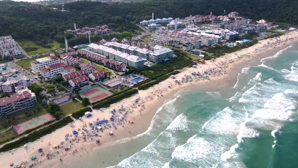 Aerial view of tropical tourist beach with hotels and summer houses facing the sea with many people alt