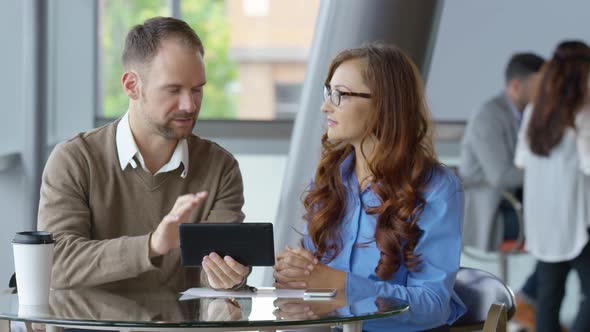 Two young business people use digital tablet