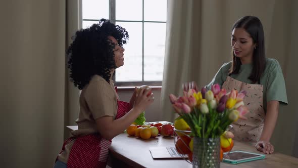Two Positive Young Women Giving Highfive Standing in Kitchen Talking and Smiling alt