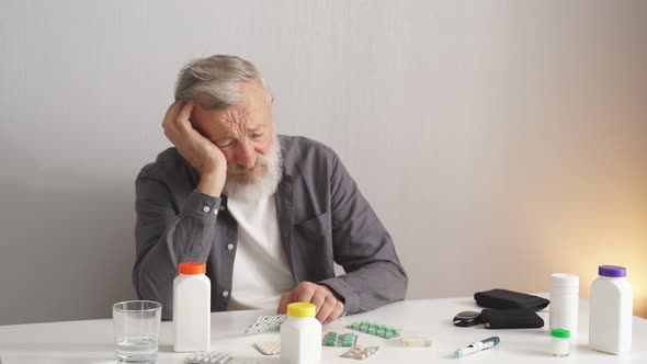 Depressed Senior Man at Home in Kitchen Sitting Behind Desk