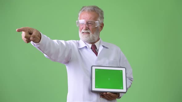 Handsome Senior Bearded Man Doctor Against Green Background alt