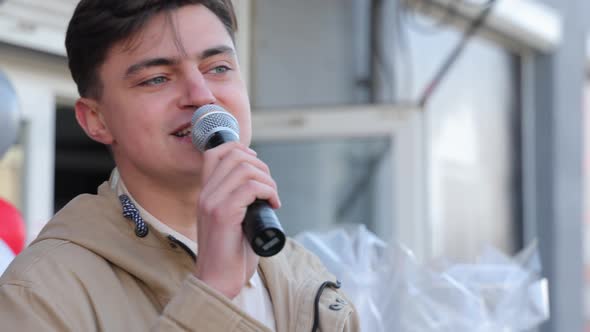 Young Man Talking Into a Microphone alt