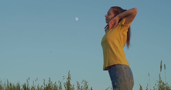 Sexy Woman in Jeans Stretching Herself on Blue Sky Background. Low Angle Side View of Young Girl alt