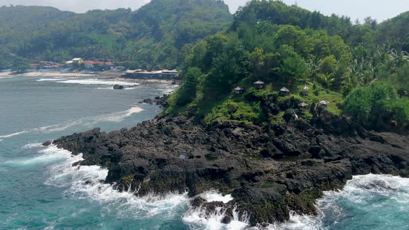 Azure ocean waves crashing on black volcanic rocks of Menganti Beach, Indonesia alt