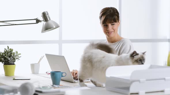 Woman working at home and cuddling her cat