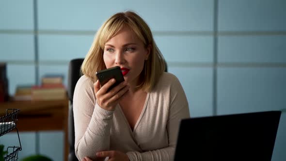Woman Is Talking on Speakerphone By Cell Phone at Office, Sending Voice Message alt
