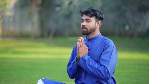 Indian man doing Namaste Yoga pose or Namaskarasana in an Indian traditional outfit Kurta Pajama alt