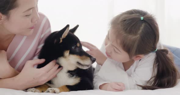 Mother and daughter playing with black dog on bed (8)