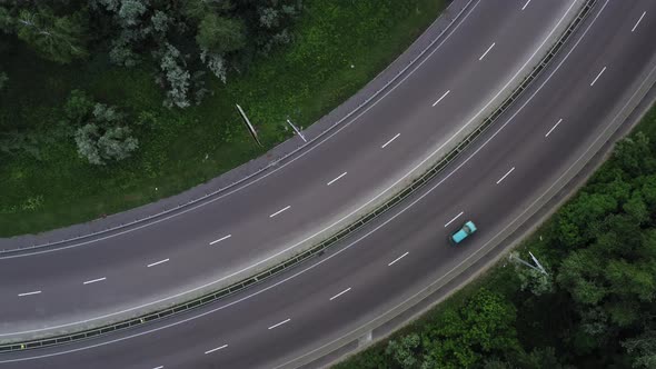 Cars and Trucks Move Along the Lanes of the Highway Among the Green Foliage  Rocket Drone Shot alt