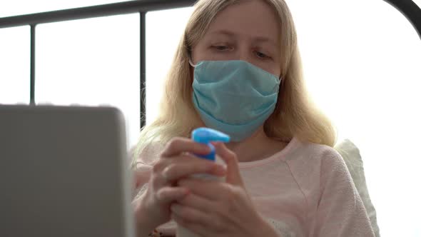 Quarantine for Coronavirus Epidemic. An Infected Masked Woman Works at Home with a Laptop.