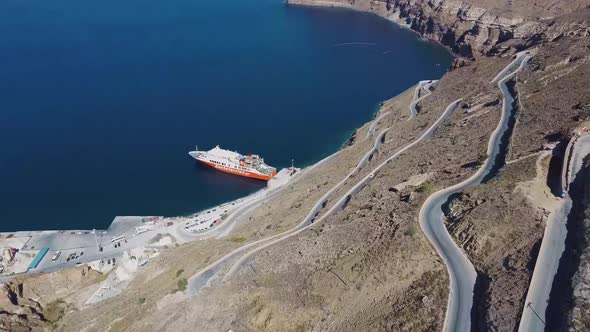 4k Aerial drone view over Santorini port winding road alt
