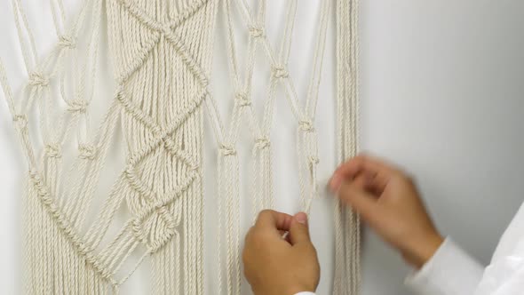 A woman weaves with her own hands a pattern of Macrame threads for decoration or home decor alt