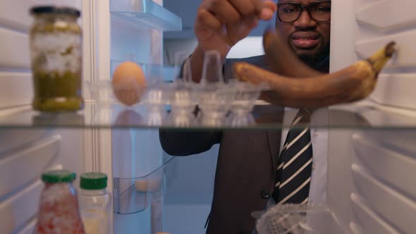 Hungry man opening fridge looking inside searching for food and disappointed.