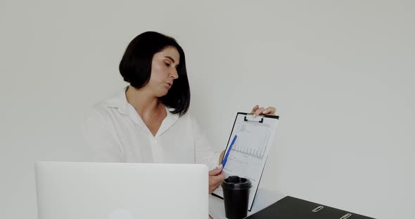 Lecturer Chatting on Laptop Using Notebook, Drinking Cup of Coffee in an Office alt