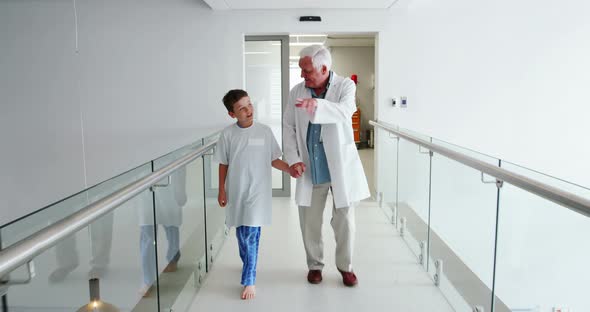 Doctor interacting with patient while walking in corridor alt