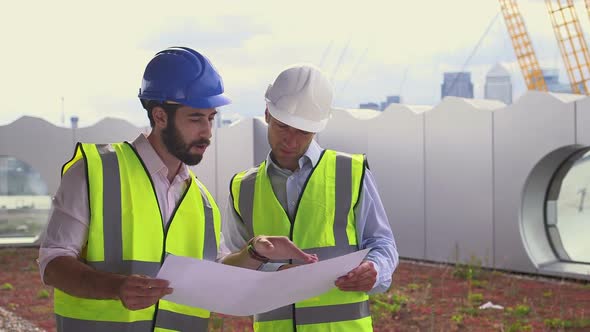 Male architect discussing with blueprint at construction site