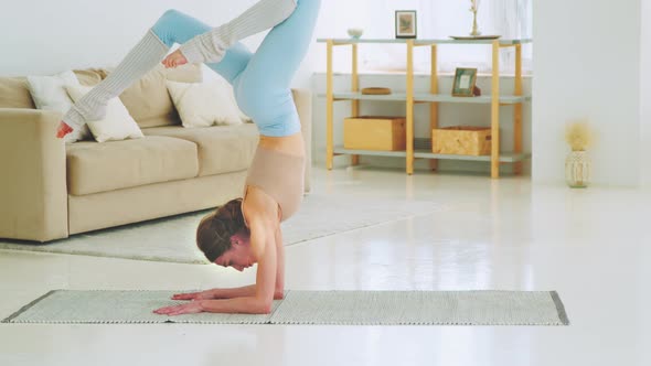 Relaxing young girl doing yoga at home. Attractive girl doing handstand alt