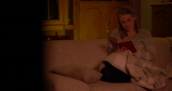 Woman Reading Book Laying on Sofa in Living Room alt
