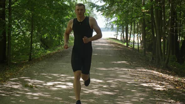 Morning Jog Pro Runner on a the Forest Road Athlete Trains in Nature Environment Triathlon alt