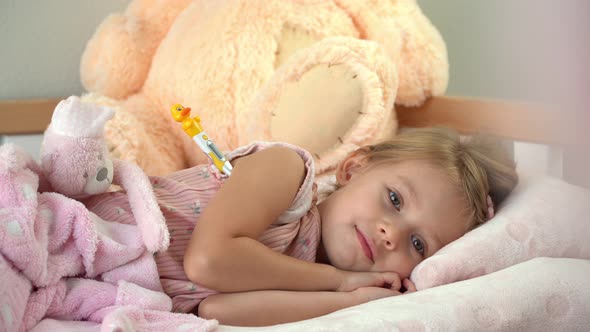 Sick Little Girl Lies in Bed at Home with Thermometer and Coughs in Sleep