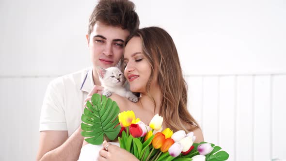 a Man Gave His Beloved Woman a Bouquet of Colorful Tulips and a White Kitten alt