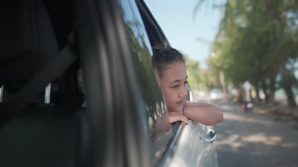 4K Asian girl kid in the car with pull her face and hand out of the window alt