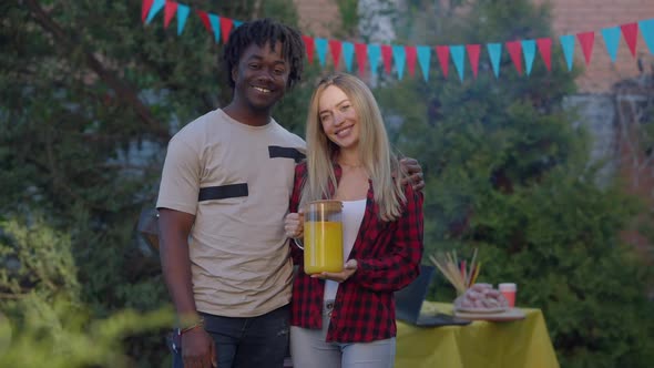 Happy Interracial Couple Posing on Picnic Outdoors Looking at Camera Smiling alt