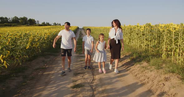 A Happy Family With Two Children Is Walking In Nature