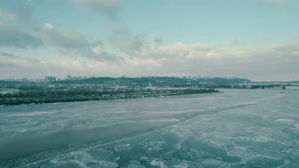 Flying Over the Frozen Dnieper River with a View of the Winter City of Kyiv