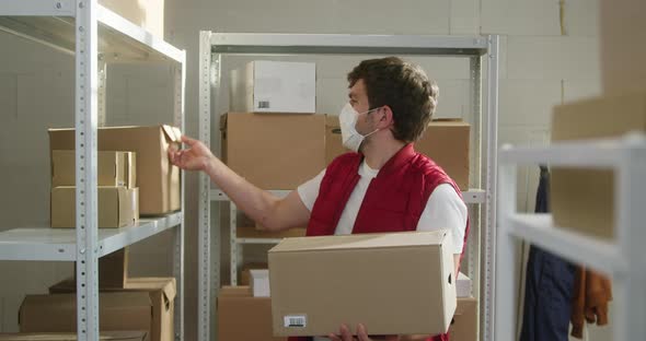 Man Wearing Red Vest Taking Parcels Employee of Warehouse in Medical Face Mask Takes Delivery Boxes alt