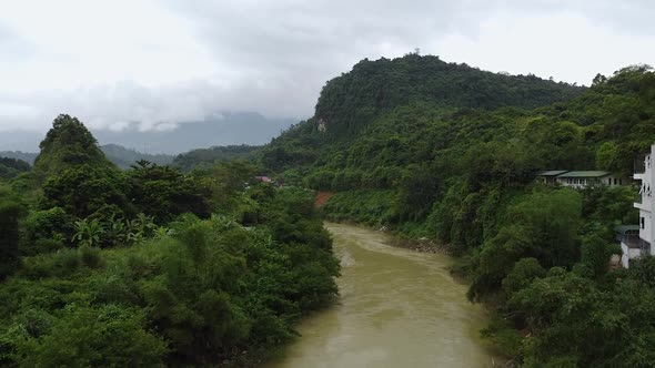 Aerial View of a Mountain River in the Mountains Around A Green Forest and Palm Trees Near Rice