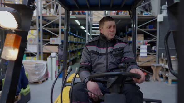 Front View Forklift Operator Driving in Large Industrial Warehouse Indoors alt