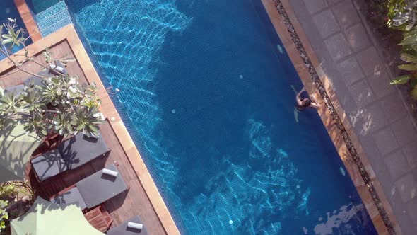 Slow Drone Shot Ascending and Rotating Above a Tropical Hotel Swimming Pool alt