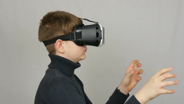 Teenager Boy Looks Into White Virtual Reality Glasses or VR and Has Fun on a White Background in the