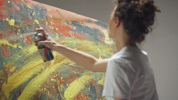 Back View Female Artist Draws with Spray Paint on a Large Canvas in a White Room a Talented Artist alt