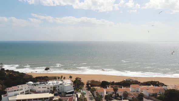 Panoramic scenic calm ocean shore with flying seagulls in Albufeira, Algarve - Pan aerial shot alt