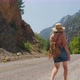 Young Woman Hiking Walks Along the Road Between High Mountains - VideoHive Item for Sale