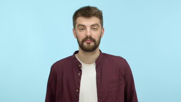 Handsome Caucasian Man with Beard Looking at Camera and Playing with Thick Eyebrows Hinting on