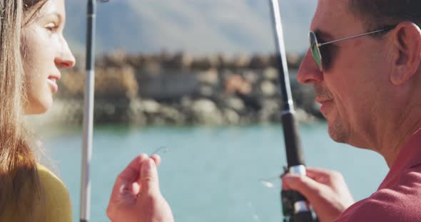 Side view close up of a Caucasian man and his teenage daughter fishing harbor side alt