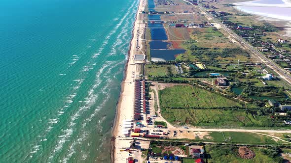 Beautiful flight in summer over the beach. People are resting near the sea. Houses for tourists. alt