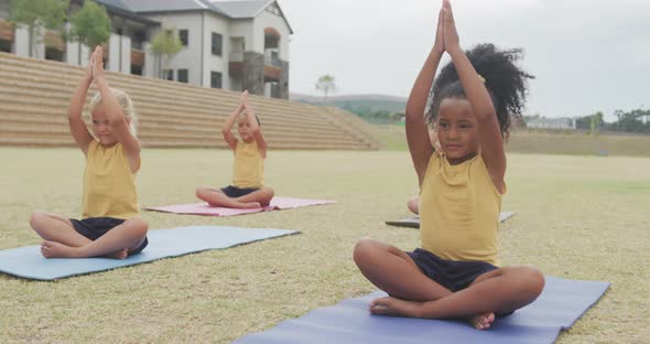 Video of focused diverse girls practicing yoga on mats in front of school alt