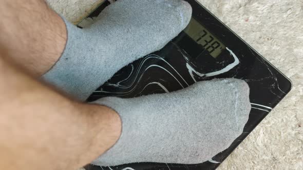 Weight Control Of A Person, Male Legs In Gray Socks Stand On Floor Scales, 77 Kg Person