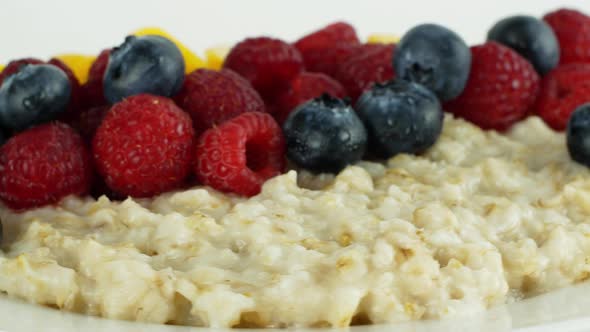 A healthy breakfast oatmeal on a plate with assorted fruits and berries, raspberries, peaches alt