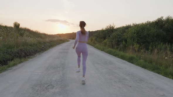 Back View of Young Lady That Running on the Road alt