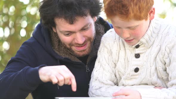 Father and son using digital tablet together